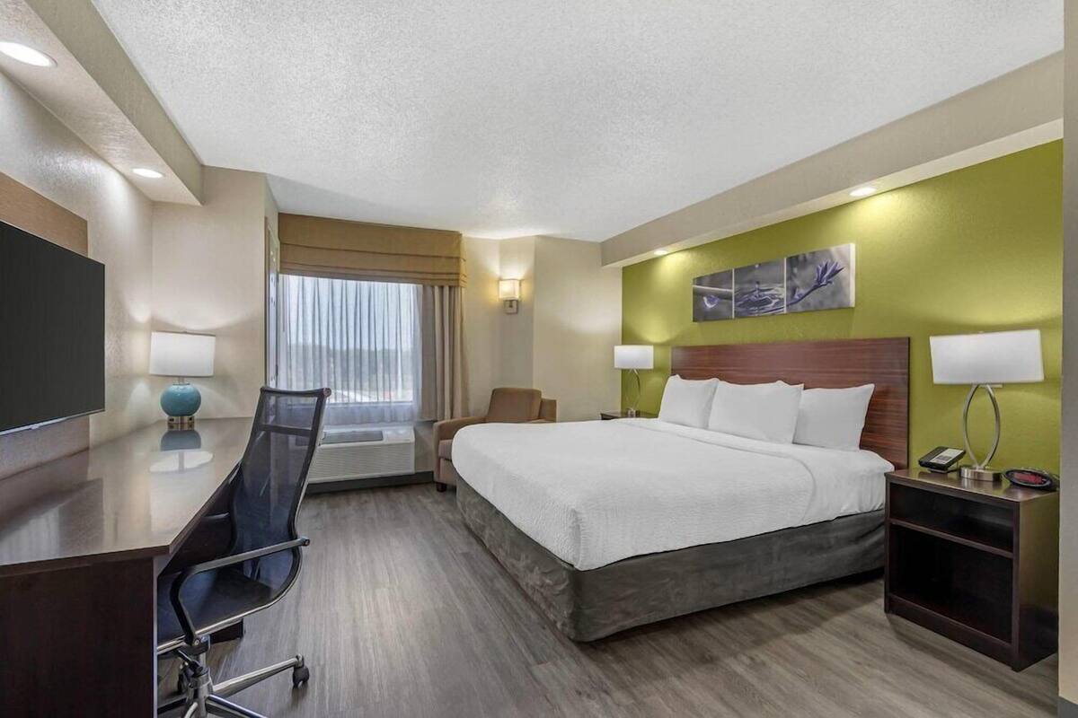 Ein Hotelzimmer mit Bett, Schreibtisch, Stuhl und Fernseher.