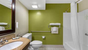 A bathroom with a granite sink, white toilet, and a shower with a white curtain.