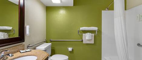 A bathroom with a granite sink, white toilet, and a shower with a white curtain.