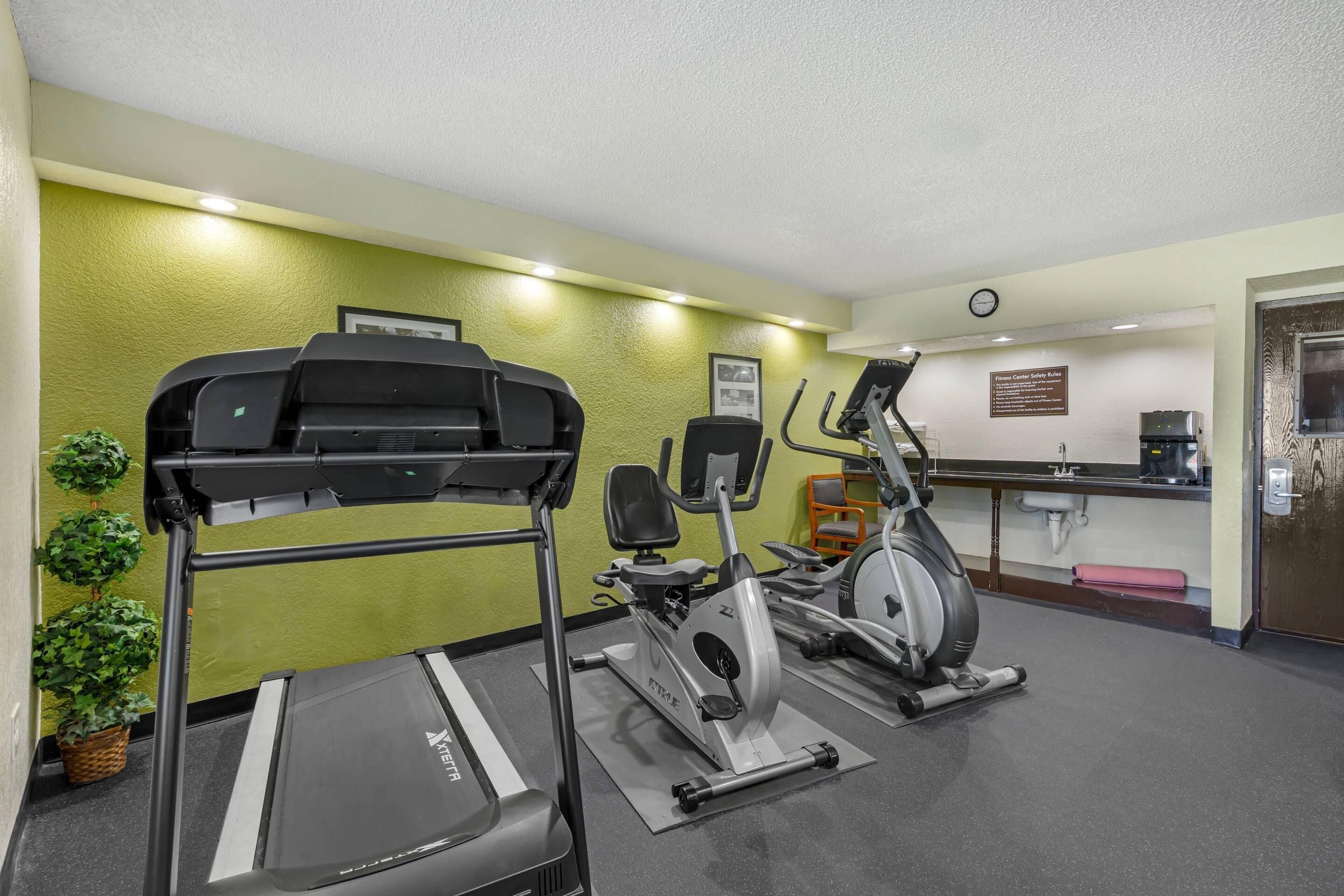 Un gimnasio con cinta de correr, elíptica y bicicleta estática.