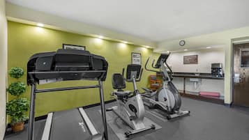 Un gimnasio con cinta de correr, elíptica y bicicleta estática.