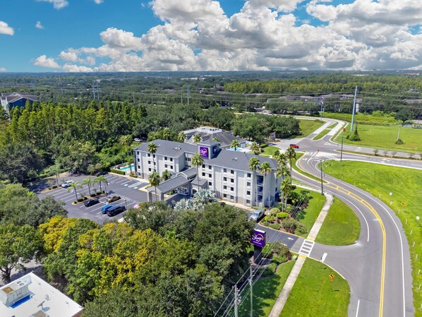 An aerial view of a hotel with multiple buildings, parking lots, and a road with traffic.