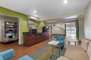Un hall de hotel con una máquina expendedora, un espacio de descanso y una recepción con una máquina de café.