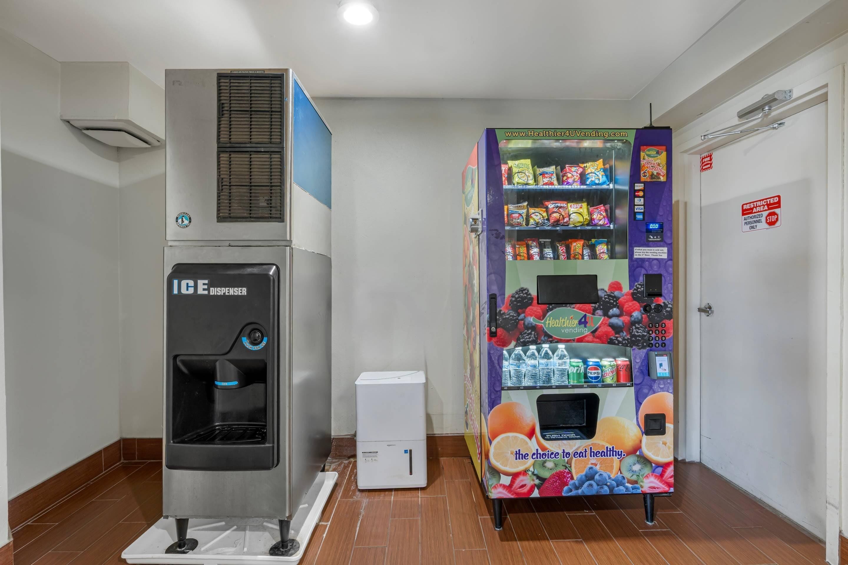 A vending machine with a variety of snacks and beverages, an ice dispenser, and a small air conditioning unit.
