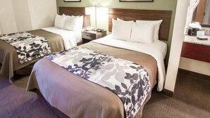 A hotel room with two beds, a nightstand, a lamp, and framed pictures on the wall. - Sleep Inn North Scottsdale near Mayo Clinic (Scottsdale)