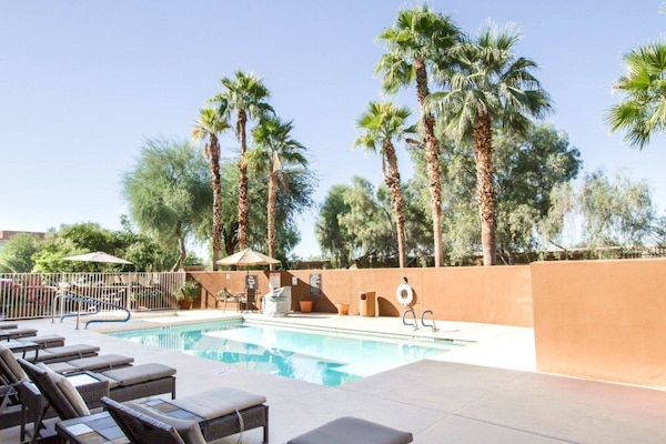 Een buitenzwembad, ligstoelen bij het zwembad