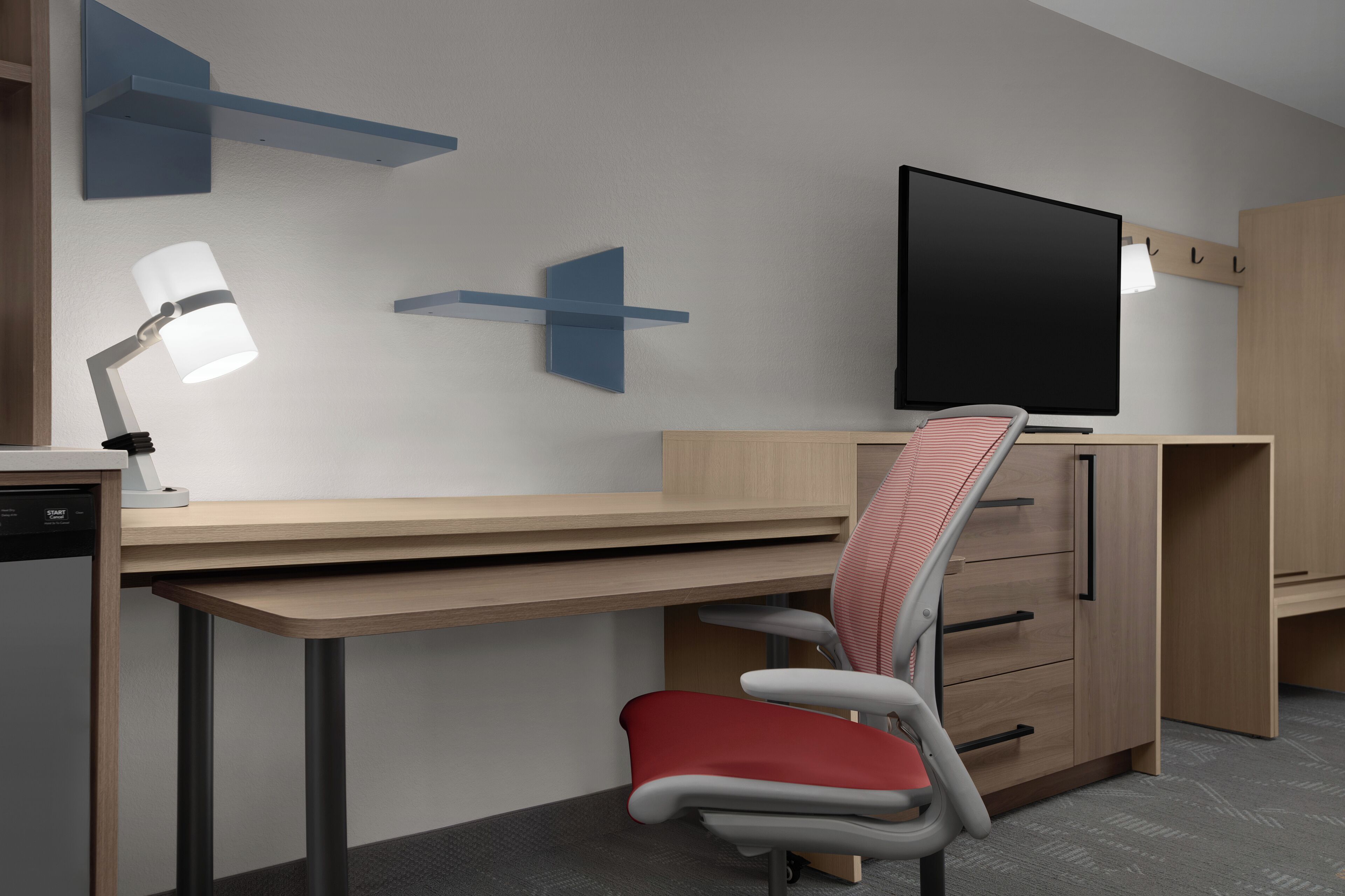A modern office space with a desk, chair, television, and shelving units.