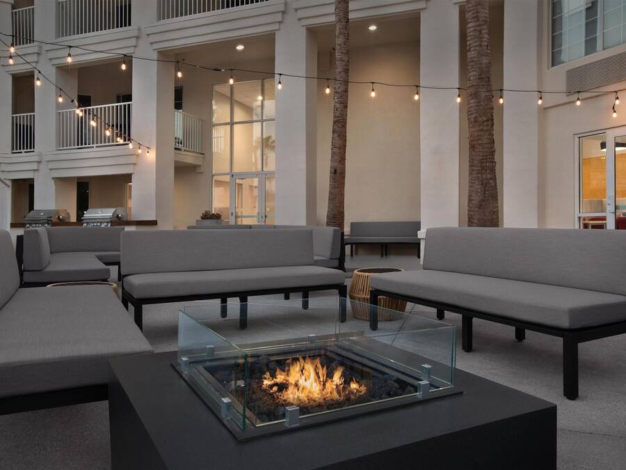 A modern outdoor seating area with sofas and a glass-top fire pit.