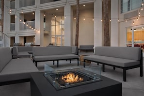 Ein moderner Außenbereich mit Sofas und einem Feuerkorb mit Glasplatte.