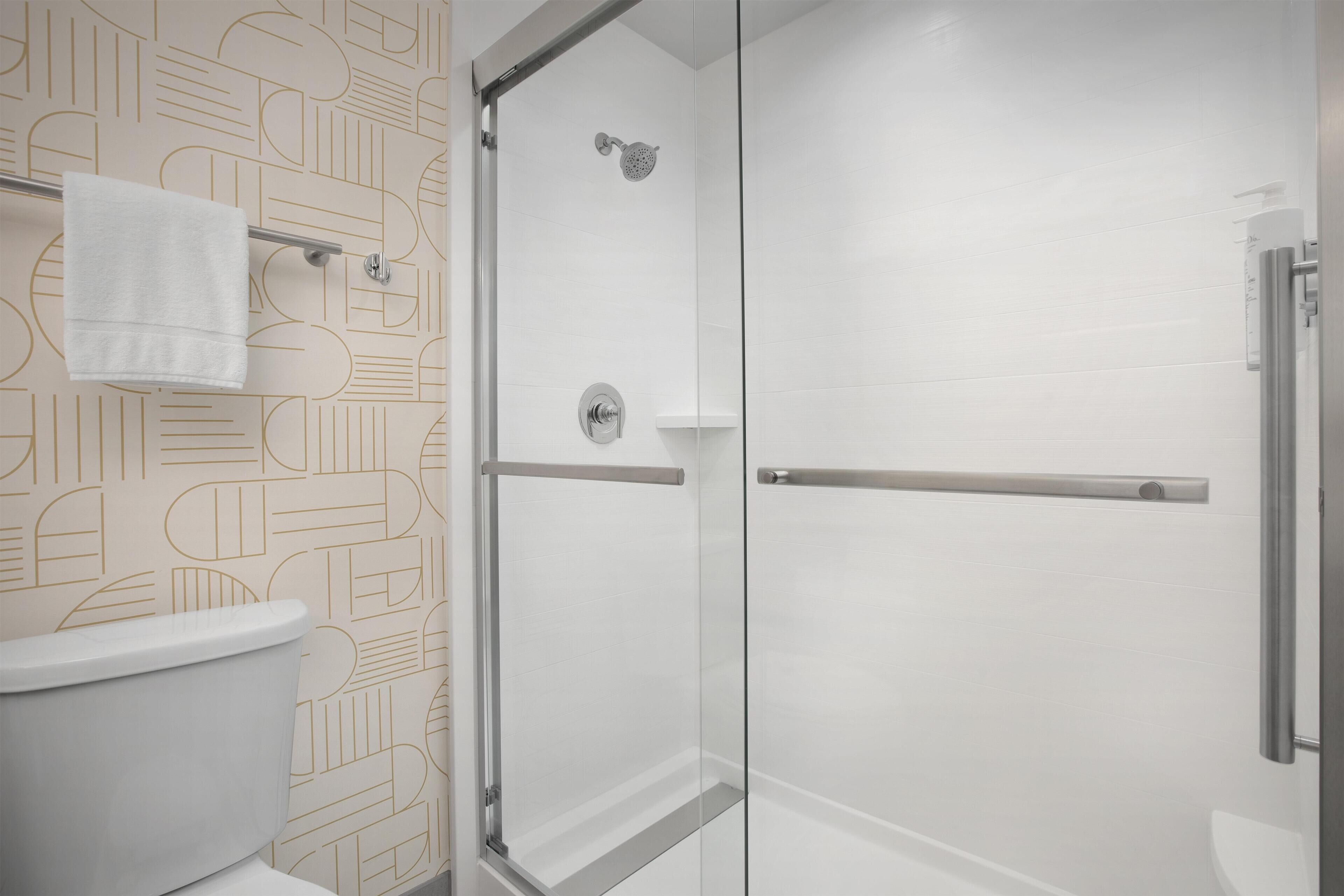 A modern bathroom with a glass shower enclosure, a toilet, and a towel rack.
