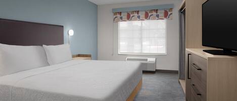 A hotel room with a bed, a television, a desk, and a window with curtains.
