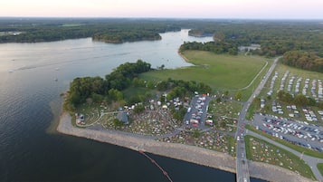 Vista aerea di un campeggio sul lago con diverse aree di parcheggio, zone picnic e un ponte che collega alla terraferma.