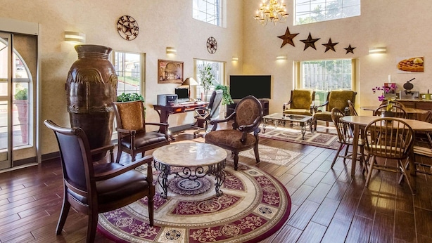 A spacious living room with a large wooden coffee table, comfortable seating, and a chandelier. - Quality Inn & Suites Kerrville (Kerrville)