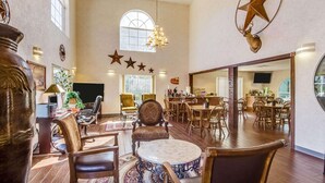 A spacious lobby with high ceilings, a chandelier, and a large mirror reflecting the dining area. - Quality Inn & Suites Kerrville (Kerrville)