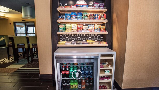 Un distributeur automatique de collations et de boissons, situé dans le hall d’un hôtel, avec des sièges et un espace d’accueil.