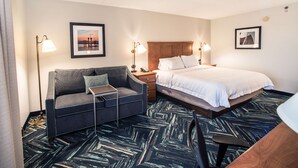 Une chambre d’hôtel avec un lit, un canapé, un bureau et une lampe.