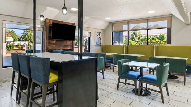 Un ristorante moderno con un'ampia sala da pranzo, diversi tavoli e sedie, e grandi vetrate che offrono vista sull'esterno.