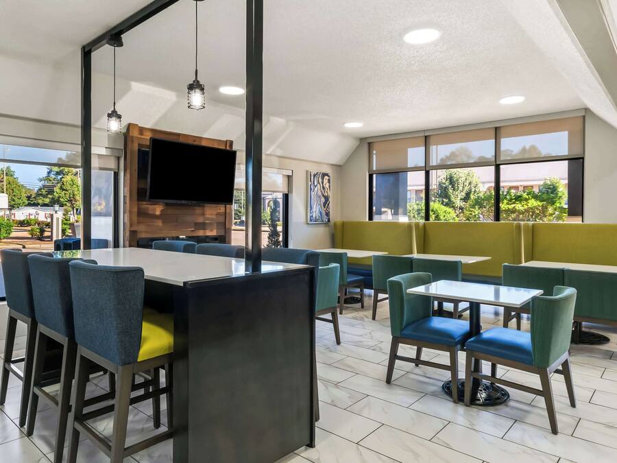 A modern restaurant with a large dining area, multiple tables and chairs, and large windows offering views of the outdoors.