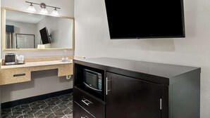 Un bagno moderno con uno specchio grande, una TV a schermo piatto, un forno a microonde e una macchina per il caffè.
