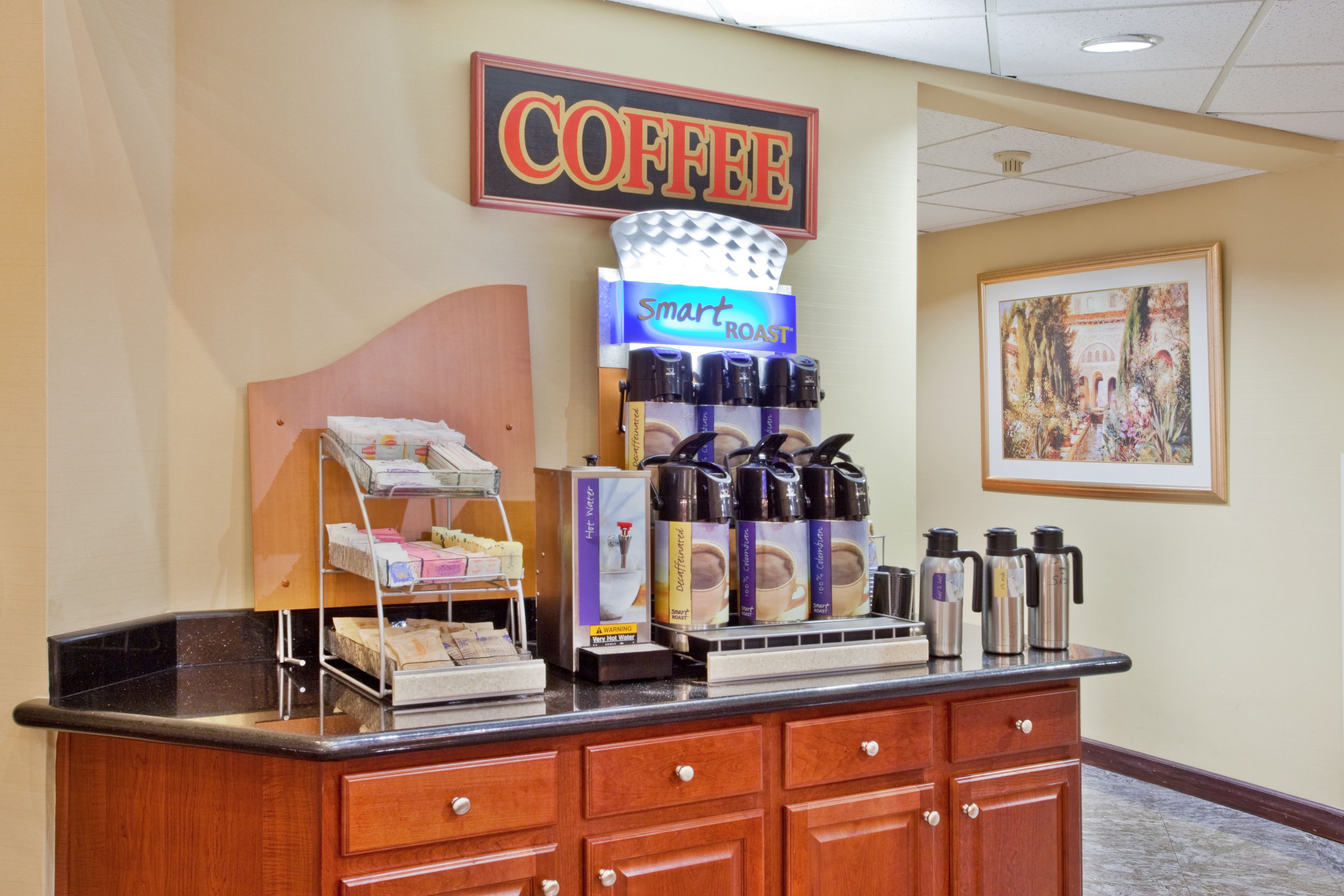 Un espace dédié au café, comprenant une machine à café, un présentoir de dosettes de café et un panneau indiquant « CAFÉ ».