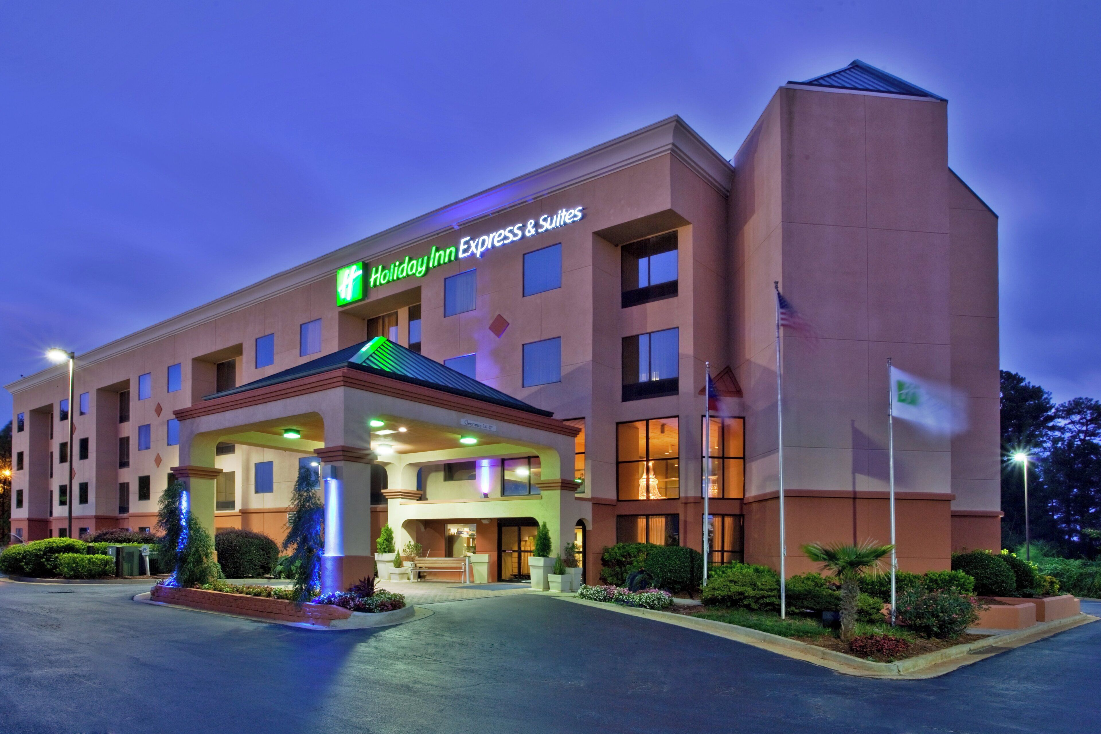 A Holiday Inn Express & Suites building with a clear entrance, a covered area with a Christmas tree, and a flagpole with an American flag.
