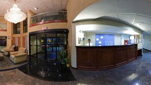 A hotel lobby with a reception desk, a chandelier, a clock, and a large window. - Holiday Inn Express Hotel & Suites by IHG (Lawrenceville)