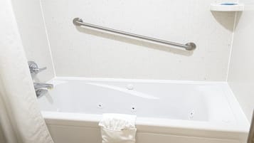 Une baignoire blanche équipée d’une barre d’appui, d’un porte-serviettes et d’un savonnetier.