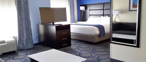 Ein Hotelzimmer mit Bett, Schreibtisch, Stuhl, Fernseher und einer Couch.