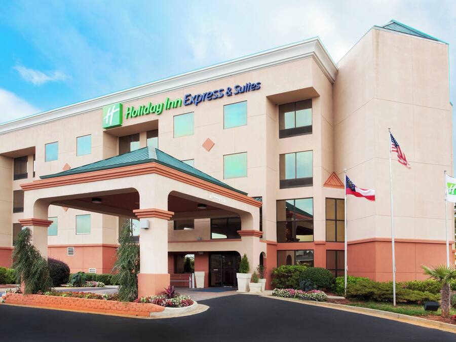 A Holiday Inn Express & Suites building with a covered entrance, multiple windows, and an American flag.