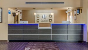 A hotel reception desk with a modern design, featuring a logo, a digital screen, and a reception counter. - Comfort Inn & Suites Perry National Fairgrounds Area (Perry)