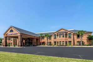 A Comfort Inn & Suites hotel with a brick facade, a covered entrance, and palm trees.
