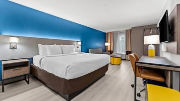Una habitación de hotel con cama, mesitas de noche, escritorio, silla y televisión.