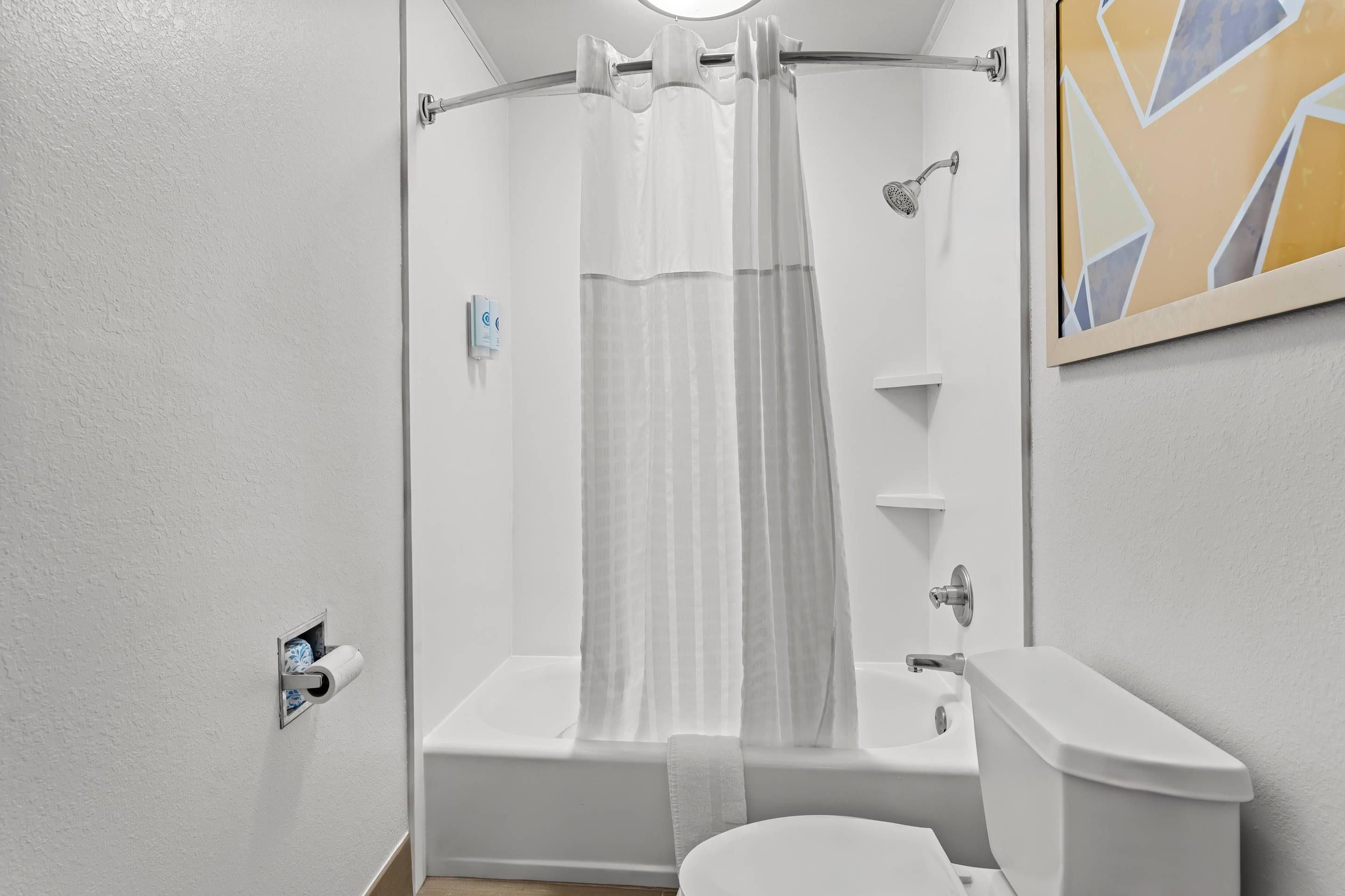 A bathroom with a bathtub, shower, toilet, and a towel rack.