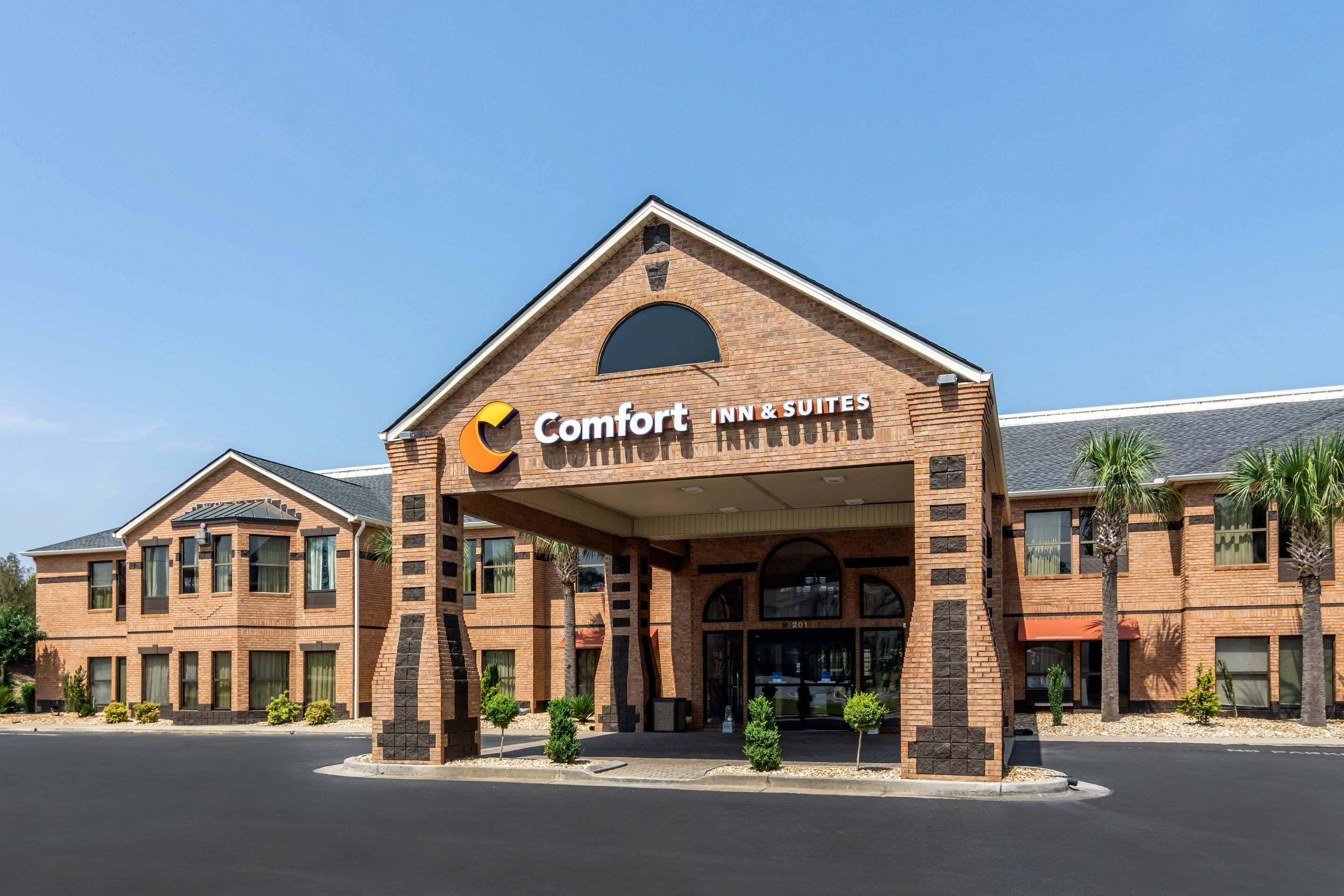 A Comfort Inn & Suites hotel with a brick facade, multiple windows, and a clear sky.