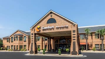 A Comfort Inn & Suites hotel with a brick facade, multiple windows, and a clear sky.