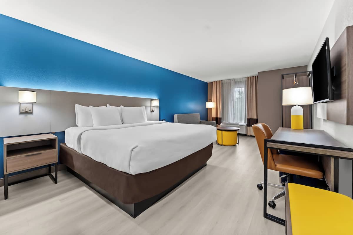 A modern hotel room with a large bed, a desk, and a chair.
