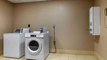 A laundry room with a front-loading washer and dryer, a utility box, and a phone on the wall.