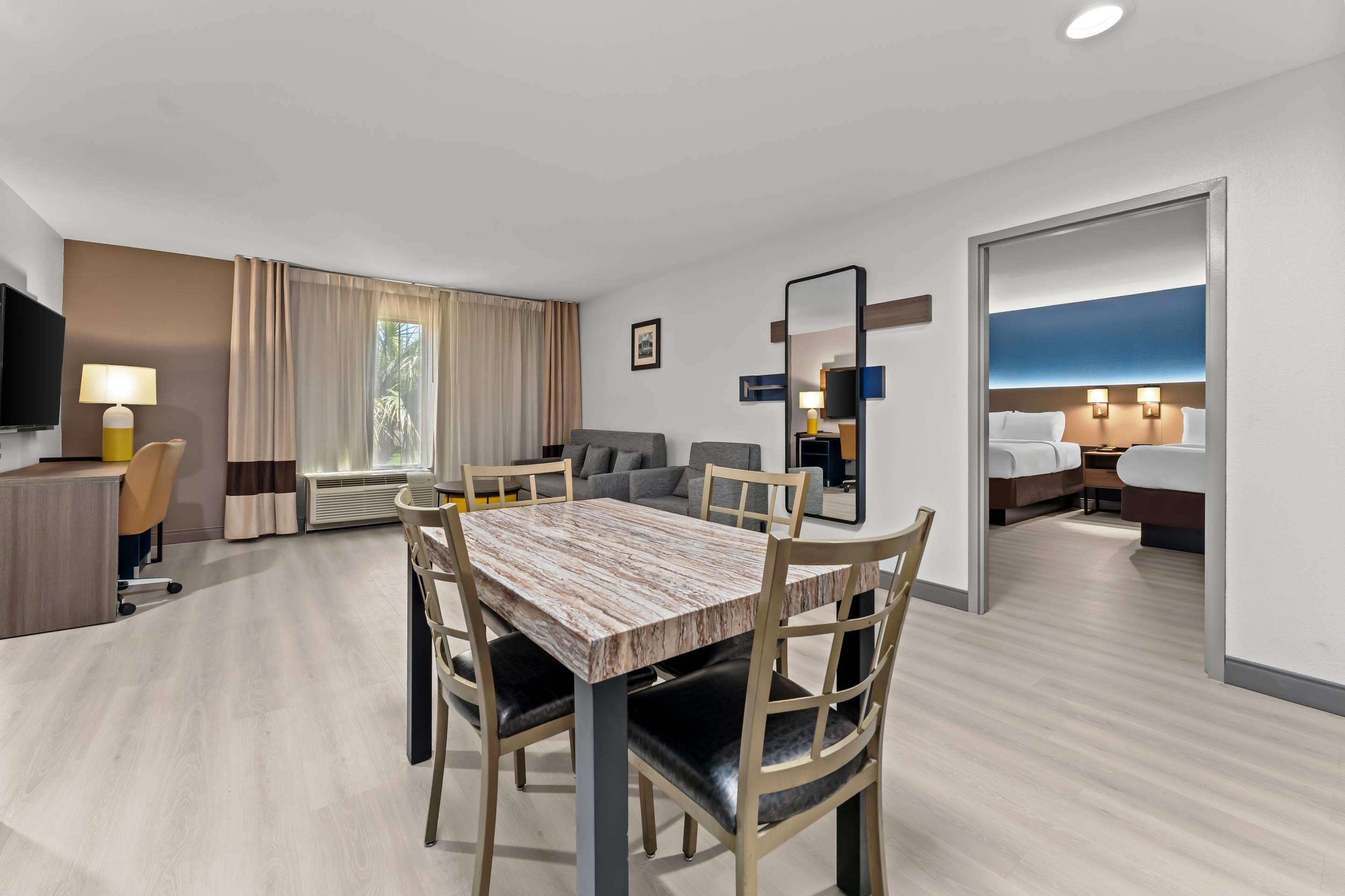 Une chambre d’hôtel comprenant un coin repas, un canapé, une télévision et un lit.