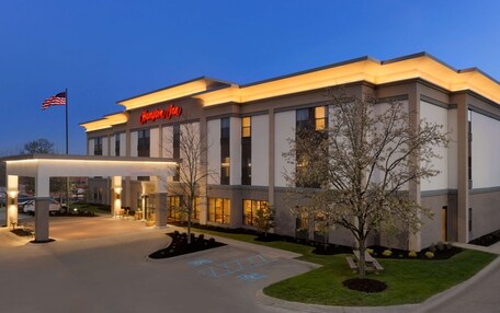 A Hampton Inn hotel with a modern facade, a covered entrance, and a well-lit parking area.