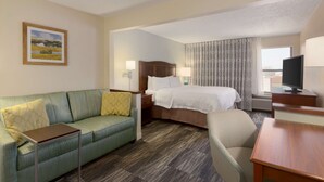 A hotel room with a bed, a sofa, a desk, and a television. - Hampton Inn Zanesville (Zanesville)