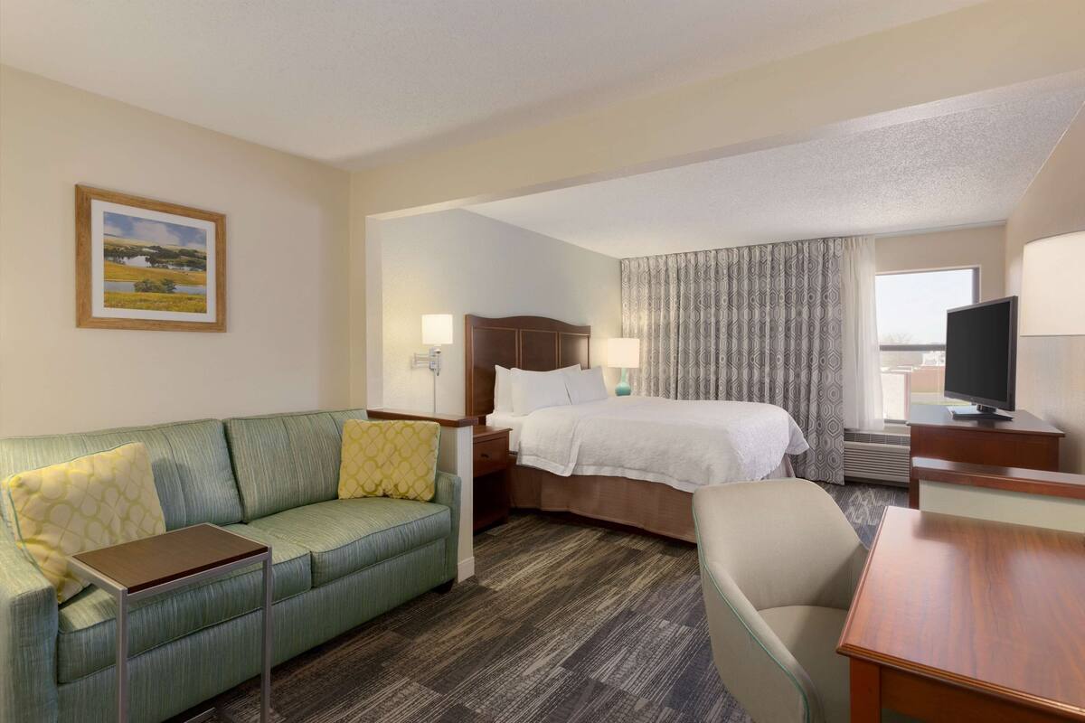 Ein Hotelzimmer mit Bett, Sofa, Schreibtisch und Fernseher.