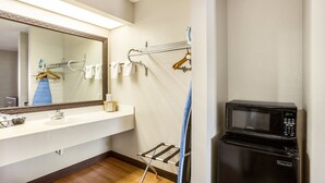 A bathroom with a sink, mirror, towel rack, and a black refrigerator.