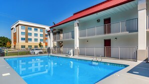 Una piscina con un edificio de techo rojo contiguo.