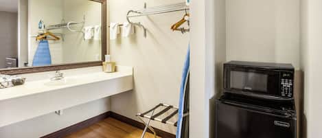 Une salle de bain d’hôtel équipée d’un lavabo, d’un miroir, d’un porte-serviettes et d’un four à micro-ondes.