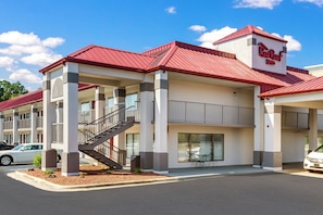 Un Red Roof Inn con un área exterior cubierta, una escalera y un coche estacionado al frente.