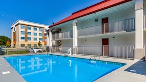 A swimming pool adjacent to a building with a red roof and balconies.