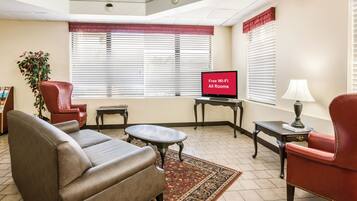A living room with a sofa, armchair, TV, and a small table.