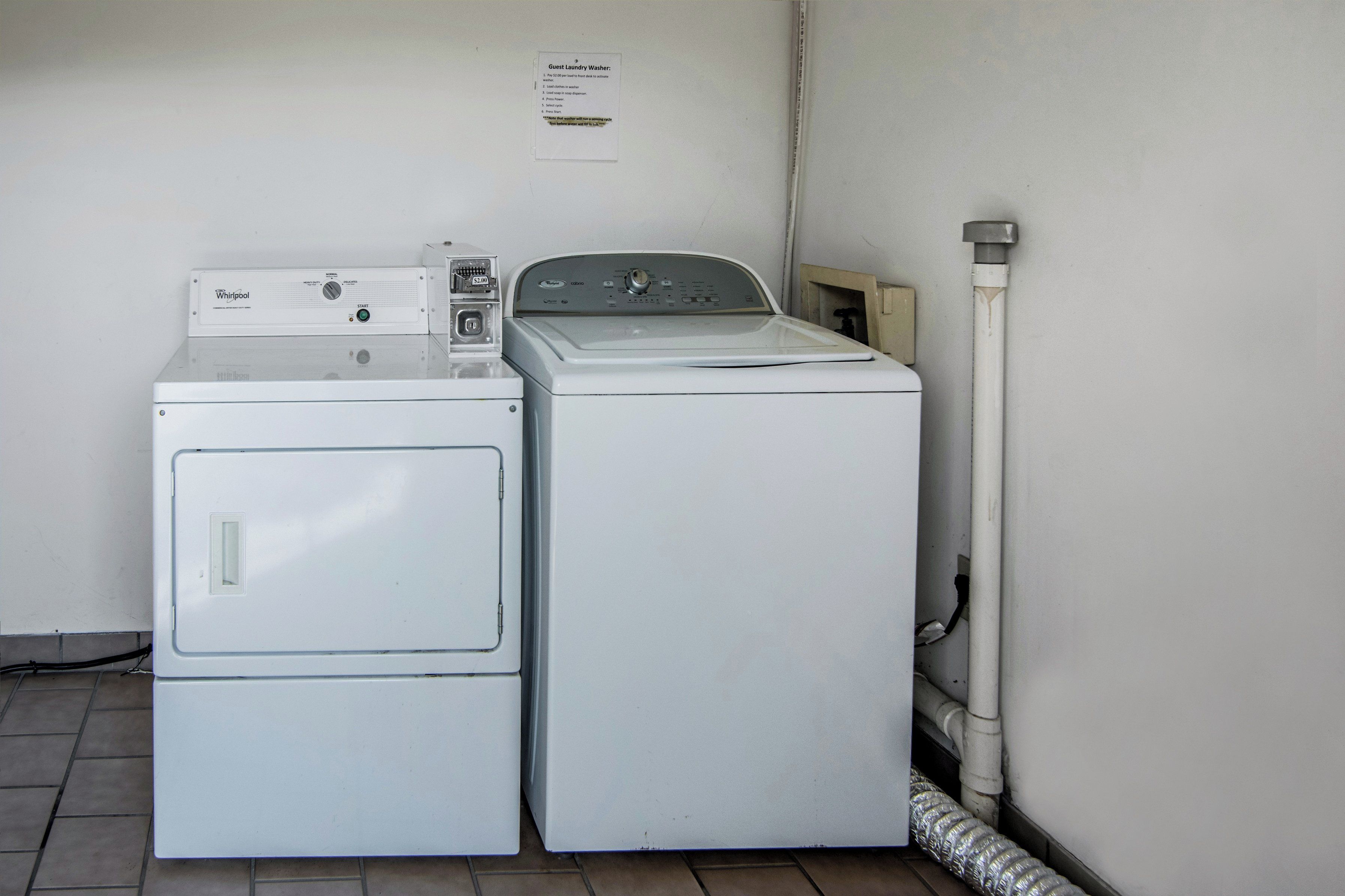 Dos lavadoras Whirlpool blancas apiladas en un cuarto de lavado, con un cartel arriba.
