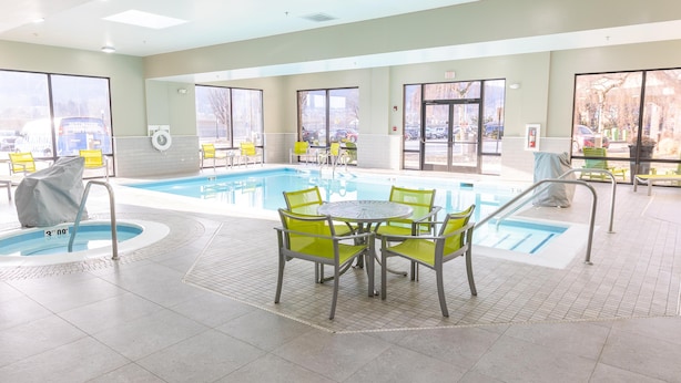 A pool area with a table and chairs, a lifeguard chair, and a pool with a tiled floor. - Hampton Inn Williamsport-Downtown (Williamsport)