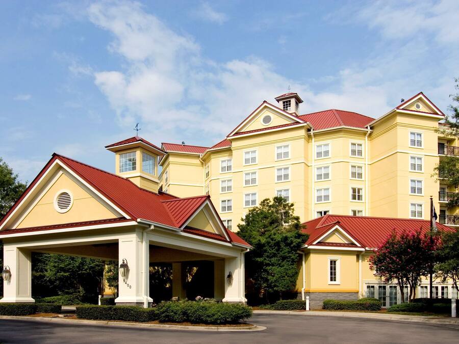 A large yellow building with a red roof, a covered entrance, and multiple windows.